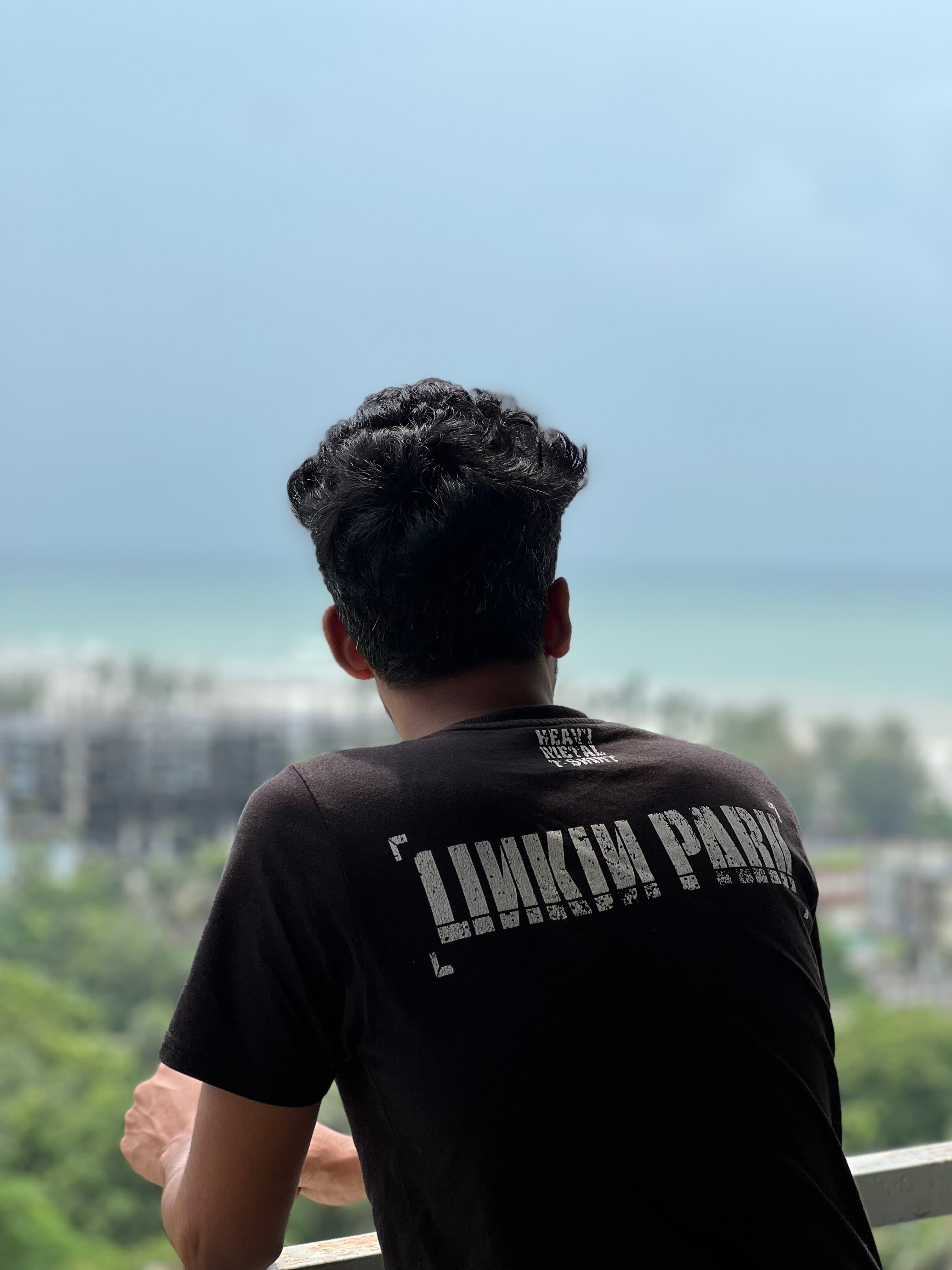 Looking out from a balcony over treetops toward a turquoise sea